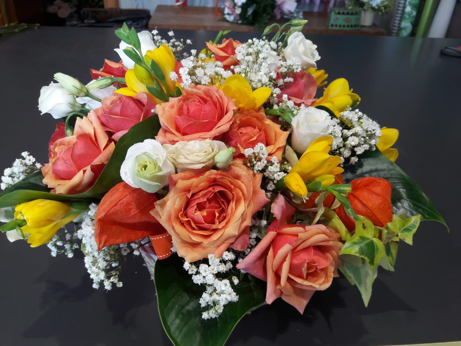 Composizione di rose arancio e pesca, fresie gialle e gypsophila