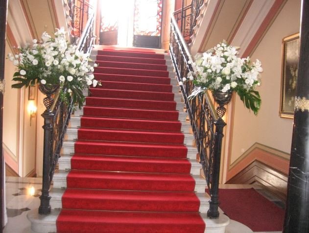 Scalinata con passatoia rossa e composizioni di fiori bianchi ai lati