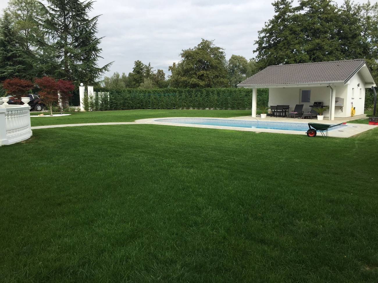Prato rasato attorno a una piscina con dépendance, in un giardino curato