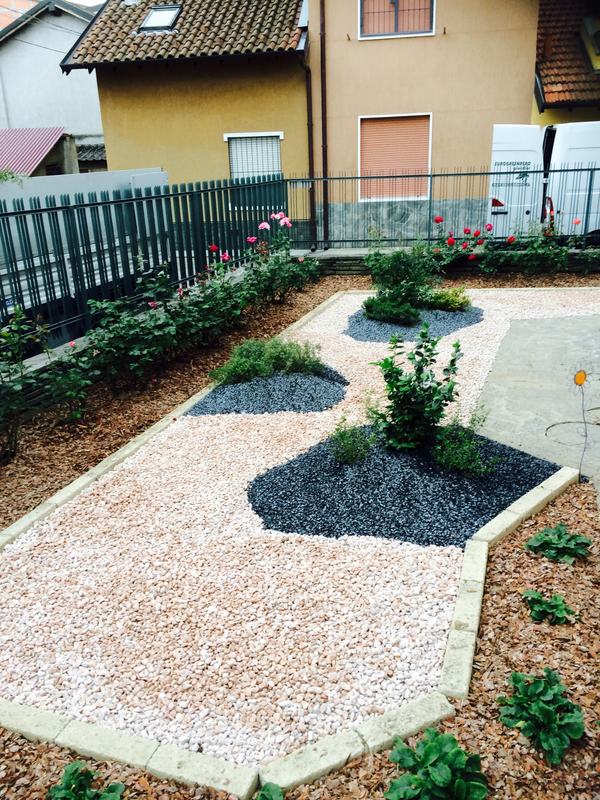 Vialetto di ghiaia bianca con aiuole di sassi neri e cespugli